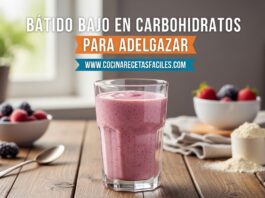 “Batido bajo en carbohidratos para adelgazar servido en un vaso alto de vidrio, sobre una mesa de madera rústica con luz natural, decorado con frutas rojas frescas.”