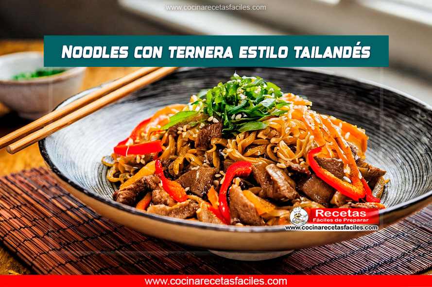 Plato de Noodles de Ternera al Estilo Tailandés servido sobre una mesa de madera con fondo de cocina luminosa