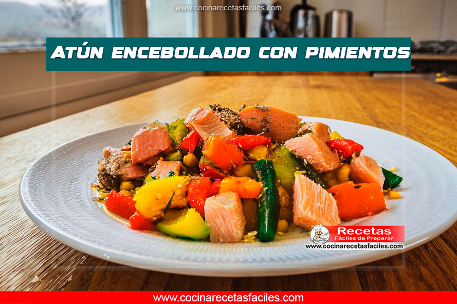 "Plato de atún encebollado con pimientos cocidos, completamente mezclado y bien dorado, con salsa brillante, servido en una mesa de madera."