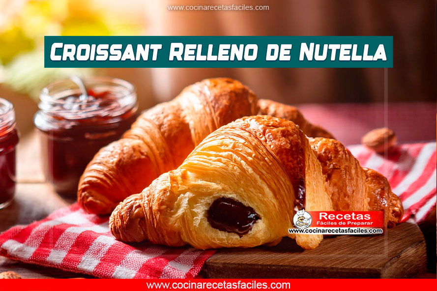 Croissant casero recién horneado sobre una mesa de madera.