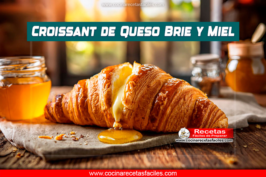 Croissant de queso brie y miel sobre una mesa de madera en una cocina cálida