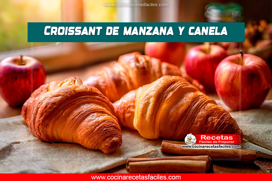 Varios croissants recién horneados de manzana y canela en primer plano, con manzanas y ramas de canela en el fondo, en un ambiente cálido de cocina.
