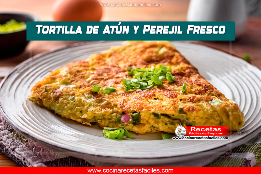 Tortilla de atún con perejil fresco y cebolla, perfectamente cocida y servida en un plato blanco sobre una mesa de madera, en el interior de una cocina con ventana grande