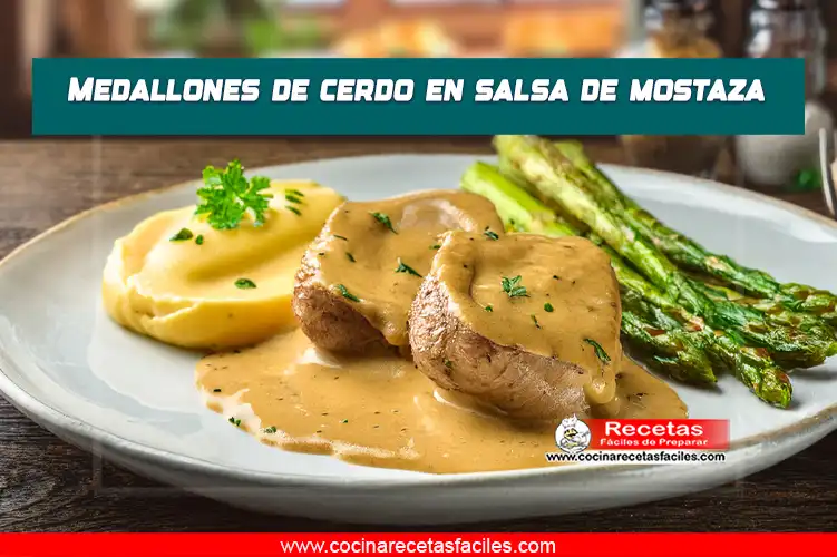 Medallones de cerdo en salsa de mostaza, servidos con puré de papas y espárragos en una mesa con mantel dentro de una cocina con ventana.